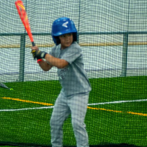 Boy holding the bat about to hit the baseball